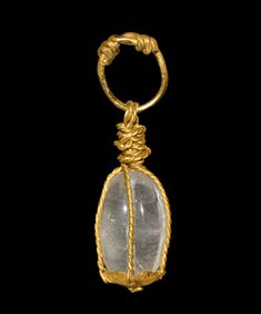 a gold pendant with a stone in the center and rope around it's neck