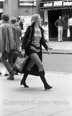 black and white photograph of woman walking down the street with shopping bags in her hand