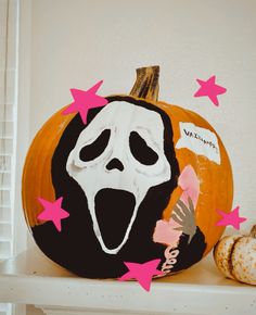 a decorated pumpkin with a ghost face and stars on the top, sitting on a shelf