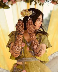 a woman with henna on her hands and flowers in her hair is posing for the camera