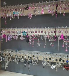 a wall mounted jewelry rack filled with lots of pink and white earrings hanging from it's sides