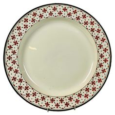 a white plate with red and black designs on the rim is sitting in front of a white background