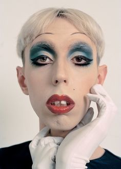 a woman with white gloves on her head and blue eyeshade, posing for the camera