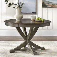 a round table with two vases on it and apples in front of the table