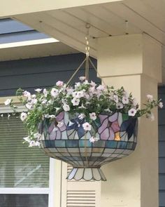 a flower pot hanging from the side of a house with stained glass flowers in it