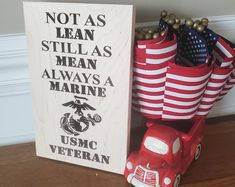 a red toy truck next to a wooden sign that says not as lean still as mean always a marine usmc veteran