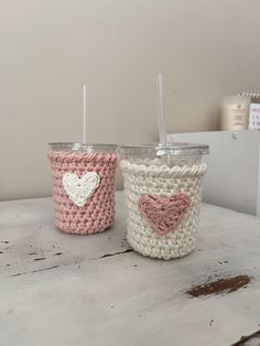 two crocheted cups with straws in the shape of hearts are sitting on a table