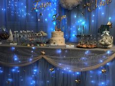 a table topped with a cake covered in frosting next to blue curtained walls