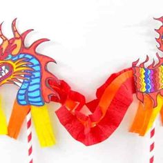 two dragon shaped kites are hanging on the wall with red and yellow streamers