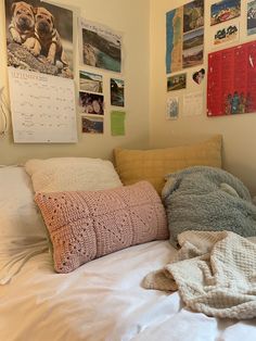 a bed with pillows and blankets on top of it next to pictures hanging on the wall