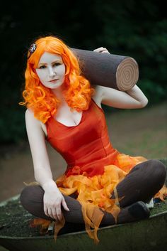 a woman with orange hair sitting on top of a tree stump holding a large piece of wood