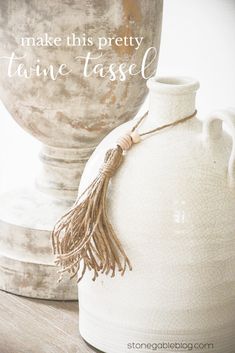 a white vase sitting on top of a wooden table next to a metal container with a tassel