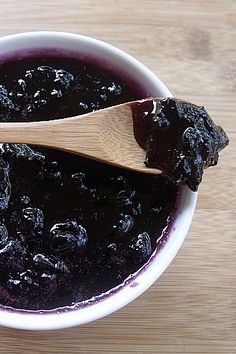 a bowl filled with blueberry sauce and a wooden spoon on top of the bowl