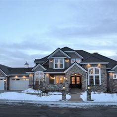 a large house with lots of windows and lights on it's front porch in the winter