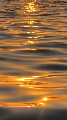 the sun is setting over the water with ripples