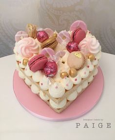 a heart shaped cake with pink frosting and gold decorations on it's sides