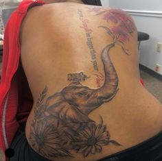 an elephant tattoo on the back of a woman's lower back, with flowers around it