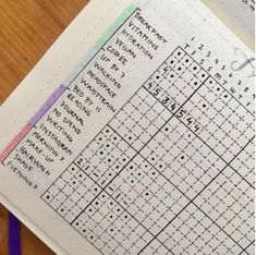 a crossword puzzle book open on a wooden table with purple markers and pencils