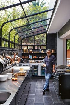 a man standing in a kitchen next to a stove top oven and counter with pots on it