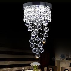 a chandelier hanging from the ceiling in a dining room with chairs and table