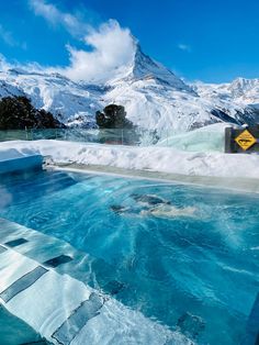 an outdoor hot tub in the middle of a snow covered mountain range with a warning sign on it