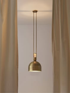 a light hanging from the ceiling in a room with curtains on either side of it