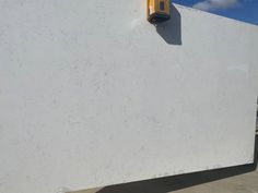 a large white marble slab with a yellow light on it's side and a blue sky in the background