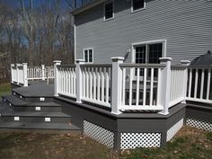 a deck with white railings in front of a house