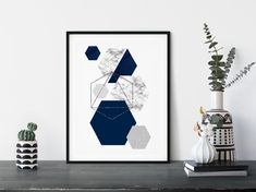 a black and white art print sitting on top of a table next to a potted plant