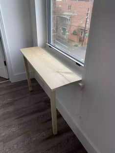 a wooden bench sitting in front of a window next to a wall and hardwood floor