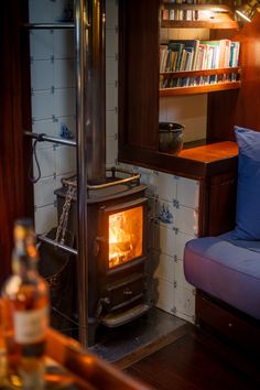 a wood burning stove sitting inside of a living room next to a blue couch and bookshelf