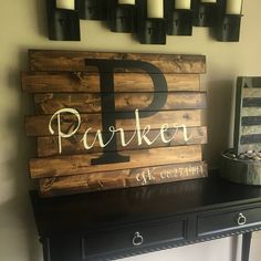 a wooden sign sitting on top of a table next to a vase and candle holders