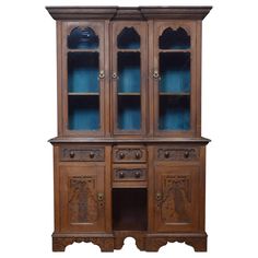 an old wooden china cabinet with blue glass doors and carvings on the front, against a white background