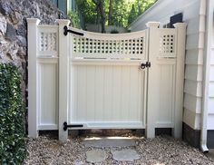 a white gate in front of a house with stone walkway leading up to the entrance