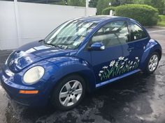 a blue car with flowers painted on it's side parked in a parking lot