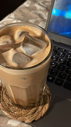 a cup of ice tea next to a laptop computer