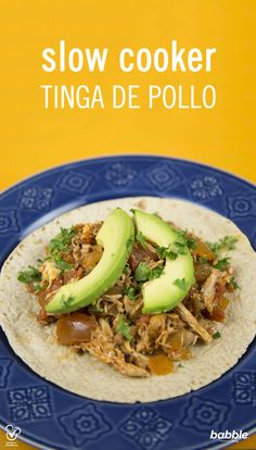 a blue plate topped with an open tortilla covered in meat and avocado