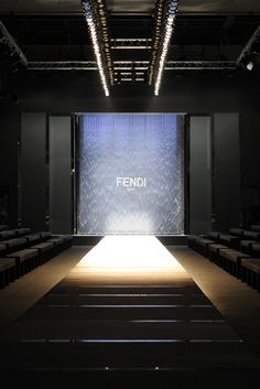 an empty stage with rows of seats and the word fendi projected on the wall