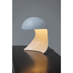 a white table lamp sitting on top of a wooden table next to a gray wall