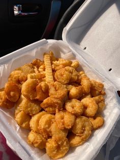 a plastic container filled with fried food sitting on top of a car seat next to a steering wheel