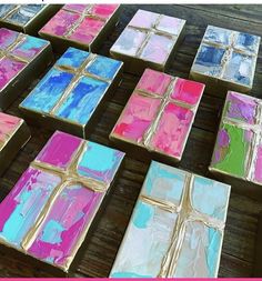 many square pieces of art are painted in pink, blue, and green with gold foil