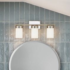 a bathroom with a round mirror and two lights on the wall next to a sink