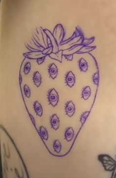 a drawing of a strawberry on the side of a woman's stomach with eyeballs all over it