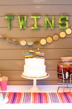 a table topped with a cake and cupcakes next to a sign that says twins