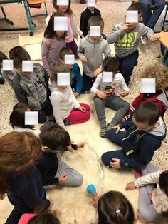 a group of children sitting on the floor in front of each other with faces taped to them