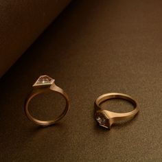 two wedding rings sitting next to each other on top of a brown surface with a diamond in the middle