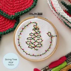 a cross stitch christmas ornament and some crochet work on a table