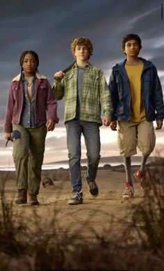 three young men walking down a dirt road