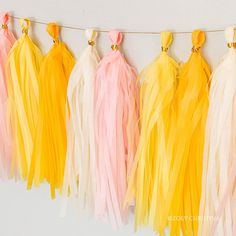 tissue tassels hanging on a line with yellow, pink and white streamers