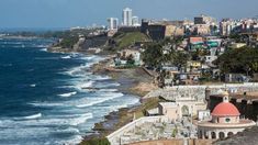 an ocean view with buildings in the background and waves crashing on the beach below it